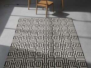 A bold, high-contrast, black and white rug with a complex interlocking geometric pattern.