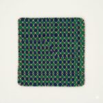 A small, square jewel-toned accent rug in sapphire blue and emerald green.