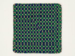 A small, square jewel-toned accent rug in sapphire blue and emerald green.