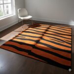 A bold and modern area rug with alternating stripes of deep black and vibrant burnt orange.