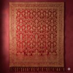 A luxurious wall tapestry in brilliant red with intricate, shimmering gold patterns, inspired by a wedding sari.
